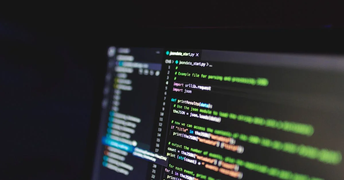 Code de programmation sur un écran d'ordinateur dans une pièce sombre, mettant en avant la technologie et l'expertise IT.