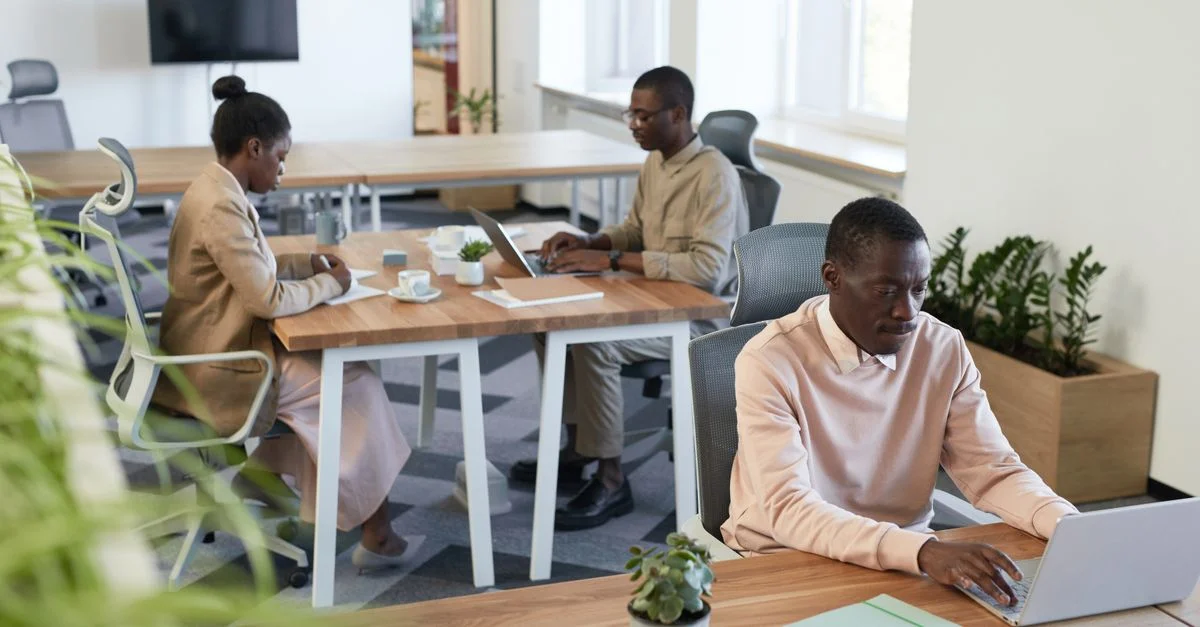 Groupe divers travaillant dans un bureau moderne avec des ordinateurs portables et des bureaux en bois.