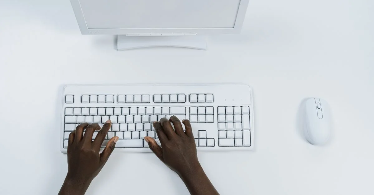 Vue de dessus des mains tapant sur une configuration d'ordinateur blanc avec souris.